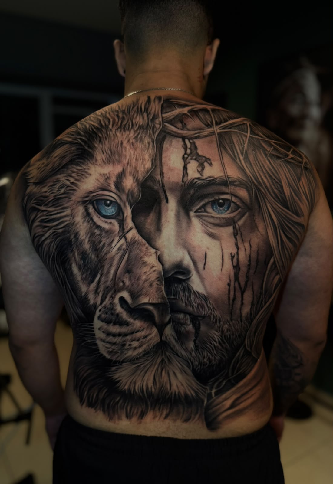 Tatuagem realista de leão e Cristo em composição de costas fechadas