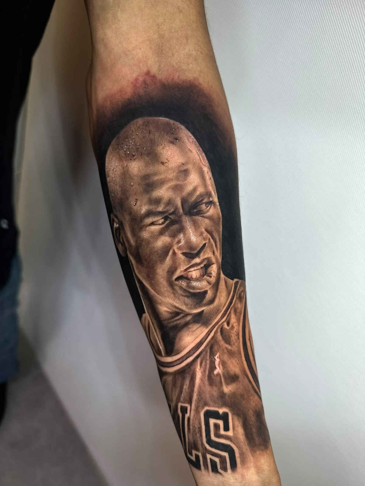 Tatuagem realista de retrato de jogador de basquete em antebraço