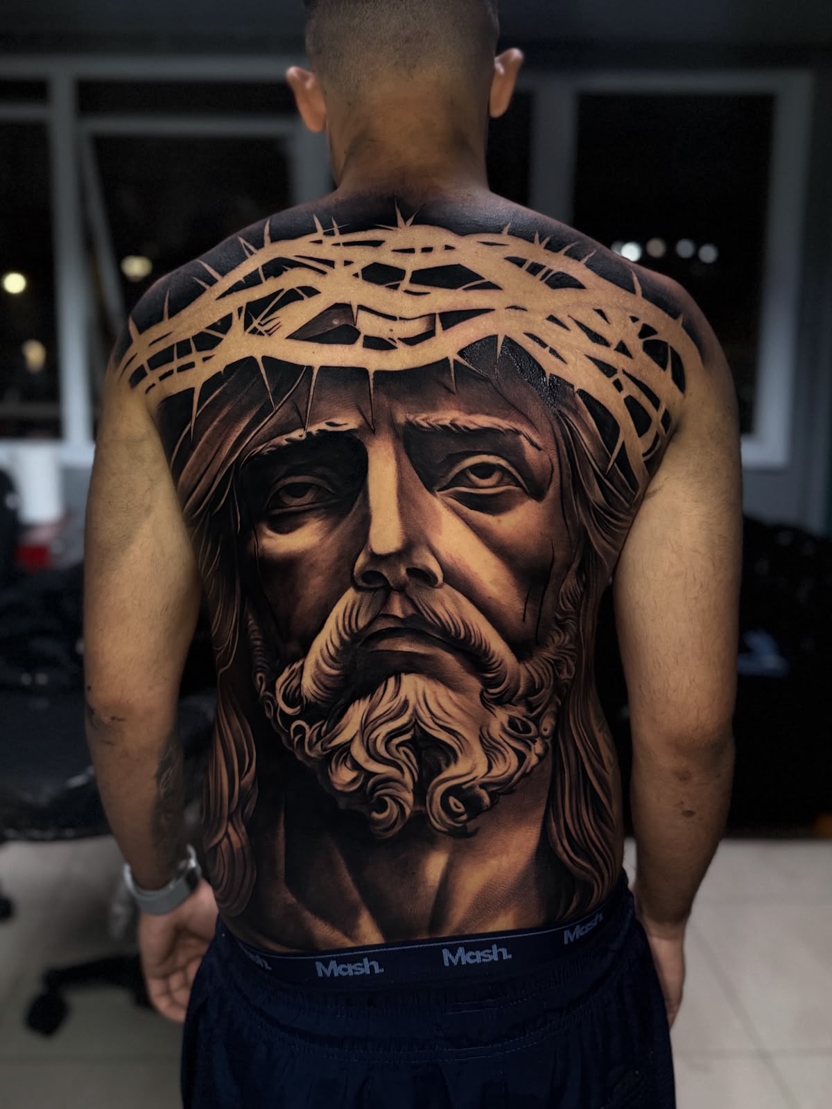 Tatuagem realista de face de Cristo com coroa de espinhos nas costas